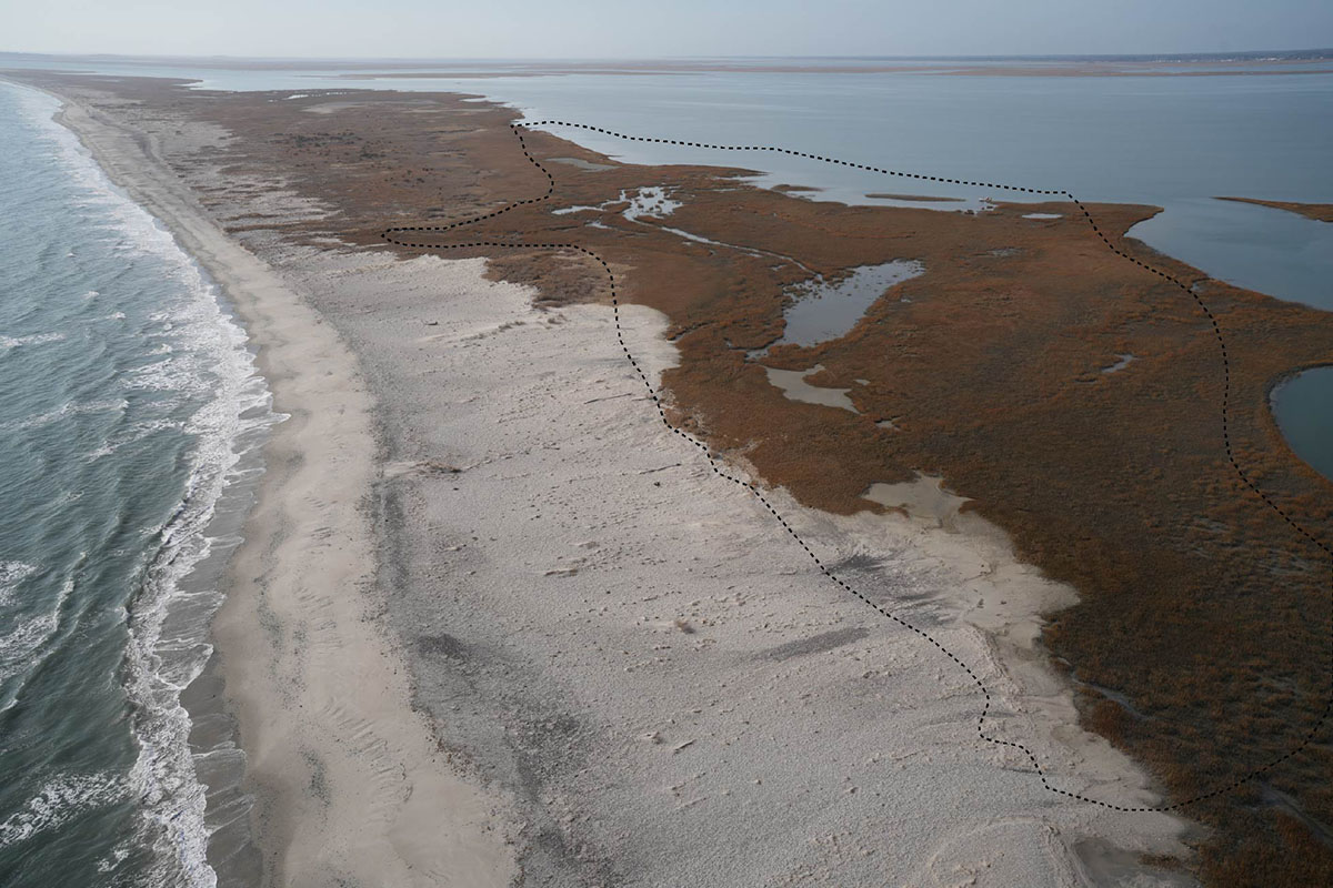 A drone photo of Cedar Island from January 2026 with the approximate location of the project site outlined. The design plan proposes relocating a thin layer of sand from a nearby flood tidal delta to stabilize the lagoon side of the island at the site of a former breach. Photo by Emily Hein.