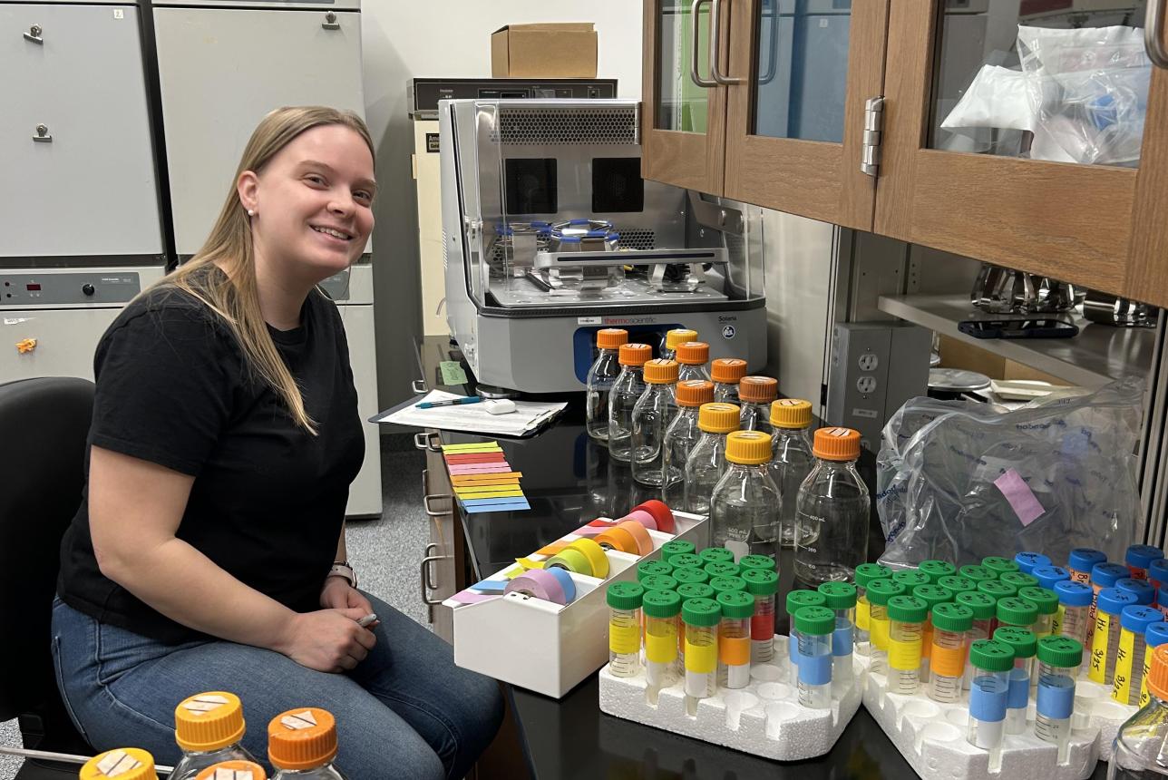A lab worker sits next to molecular assay equipment